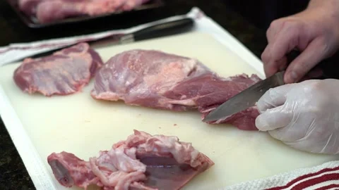 Man Cutting and trimming Large Pork Meat In A Kitchen With Two Knives Stock Footage 140604365
