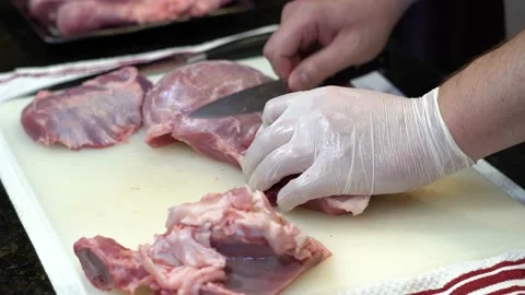 Man Cutting and trimming Large Pork Meat In A Kitchen With Two Knives Video stock 140607113