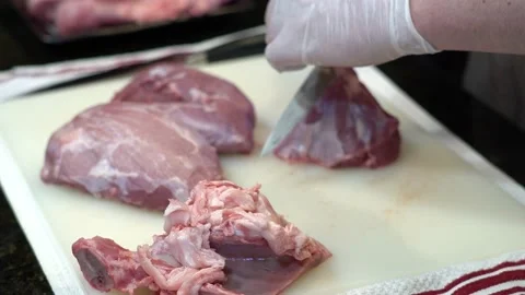 Man Cutting and trimming Large Pork Meat In A Kitchen With Two Knives Stock Footage 140607343
