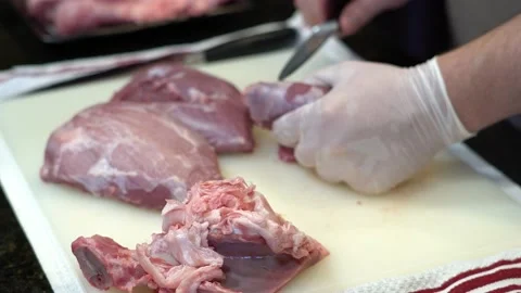 Man Cutting and trimming Large Pork Meat In A Kitchen With Two Knives Stock Footage 140607348