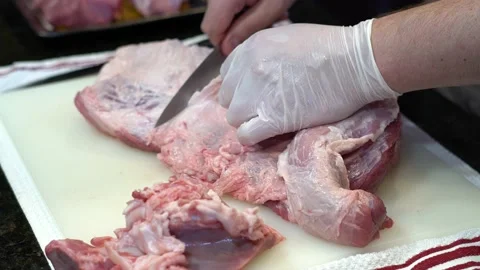 Man Cutting and trimming Large Pork Meat In A Kitchen With Two Knives Stock Footage 140608116