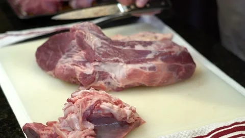 Man Cutting and trimming Large Pork Meat In A Kitchen With Two Knives Stock Footage 140608435