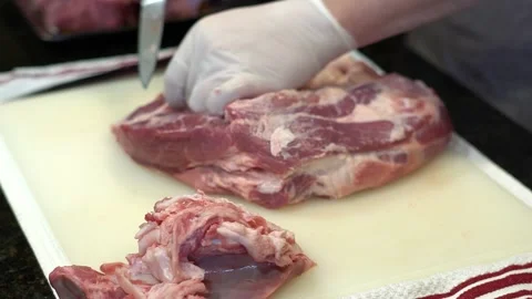 Man Cutting and trimming Large Pork Meat In A Kitchen With Two Knives Stock Footage 140608513