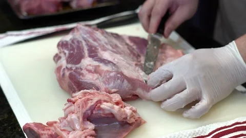 Man Cutting and trimming Large Pork Meat In A Kitchen With Two Knives Video stock 140608526