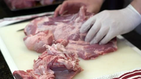 Man Cutting and trimming Large Pork Meat In A Kitchen With Two Knives Video stock 140608972
