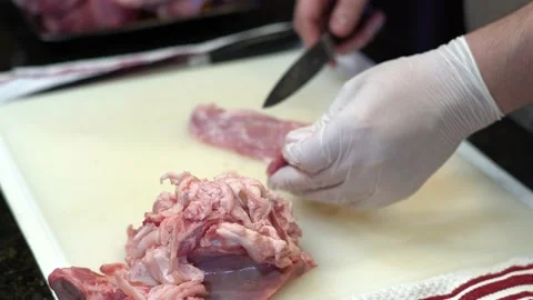 Man Cutting and trimming Large Pork Meat In A Kitchen With Two Knives Stock Footage 140609184