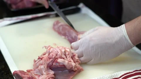 Man Cutting and trimming Large Pork Meat In A Kitchen With Two Knives Stock Footage 140609211