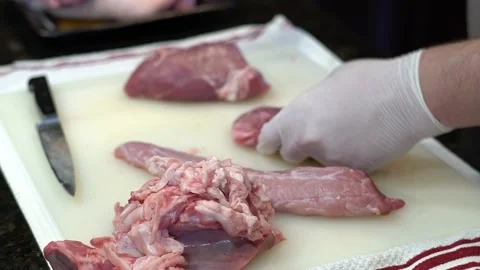 Man Cutting and trimming Large Pork Meat In A Kitchen With Two Knives Video stock 140609404