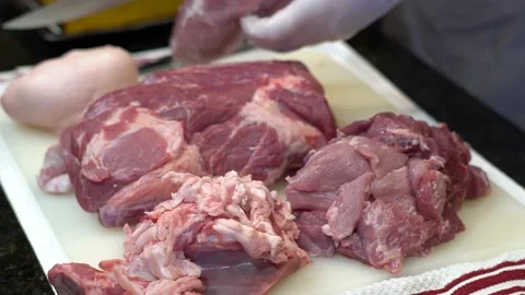 Man Cutting and trimming Large Pork Meat In A Kitchen With Two Knives Video stock 140609477