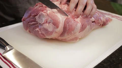 Man Cutting and trimming Large Pork Meat In A Kitchen With Two Knives Stock Footage 140610107