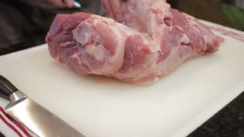 Man Cutting and trimming Large Pork Meat In A Kitchen With Two Knives Video stock 140610384