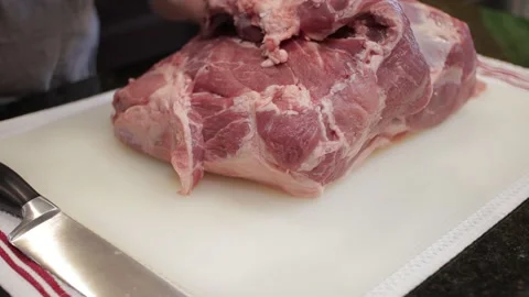 Man Cutting and trimming Large Pork Meat In A Kitchen With Two Knives Stock Footage 140610427