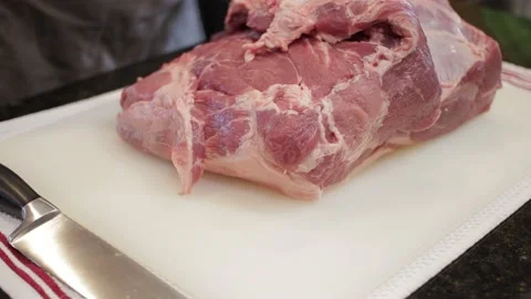 Man Cutting and trimming Large Pork Meat In A Kitchen With Two Knives Video stock 140610706