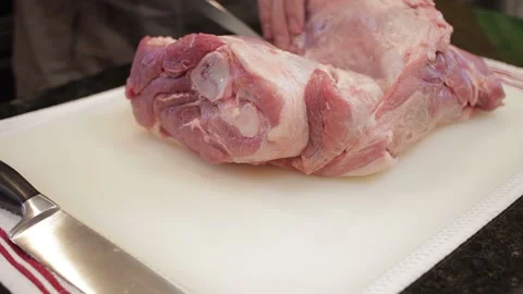 Man Cutting and trimming Large Pork Meat In A Kitchen With Two Knives Video stock 140610823
