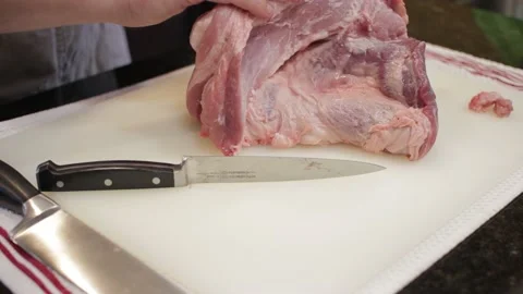 Man Cutting and trimming Large Pork Meat In A Kitchen With Two Knives Video stock 140612042