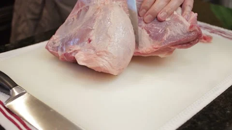 Man Cutting and trimming Large Pork Meat In A Kitchen With Two Knives Stock Footage 140612043