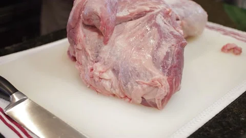 Man Cutting and trimming Large Pork Meat In A Kitchen With Two Knives Stock Footage 140612231
