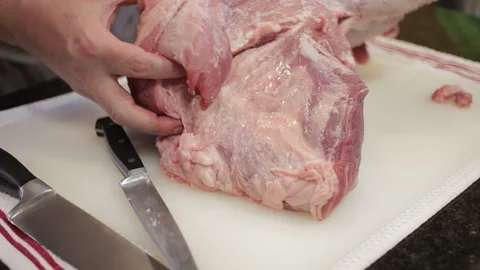 Man Cutting and trimming Large Pork Meat In A Kitchen With Two Knives Video stock 140612236