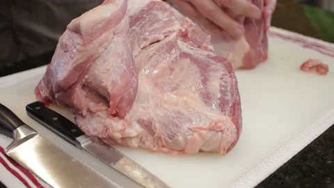 Man Cutting and trimming Large Pork Meat In A Kitchen With Two Knives Stock Footage 140612243