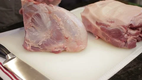 Man Cutting and trimming Large Pork Meat In A Kitchen With Two Knives Video stock 140612247