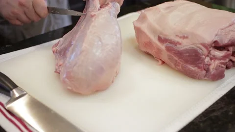 Man Cutting and trimming Large Pork Meat In A Kitchen With Two Knives Stock Footage 140612253