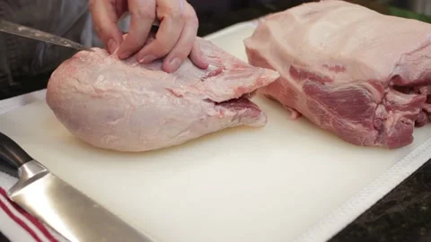 Man Cutting and trimming Large Pork Meat In A Kitchen With Two Knives Video stock 140612480