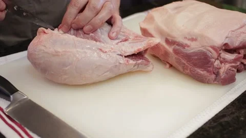 Man Cutting and trimming Large Pork Meat In A Kitchen With Two Knives Stock Footage 140612508