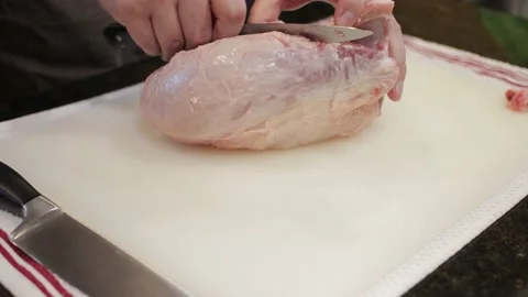 Man Cutting and trimming Large Pork Meat In A Kitchen With Two Knives Video stock 140612747