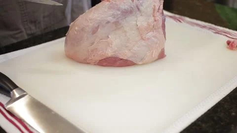 Man Cutting and trimming Large Pork Meat In A Kitchen With Two Knives Stock Footage 140612759