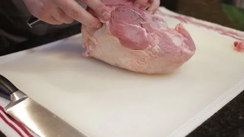 Man Cutting and trimming Large Pork Meat In A Kitchen With Two Knives Video stock 140612760