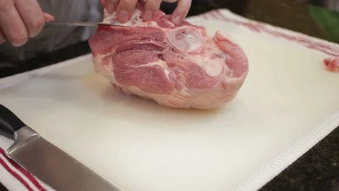 Man Cutting and trimming Large Pork Meat In A Kitchen With Two Knives Video stock 140612762