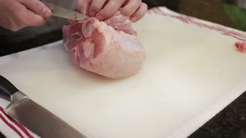 Man Cutting and trimming Large Pork Meat In A Kitchen With Two Knives Stock Footage 140613113