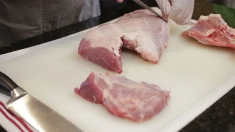Man Cutting and trimming Large Pork Meat In A Kitchen With Two Knives Stock Footage 140614772