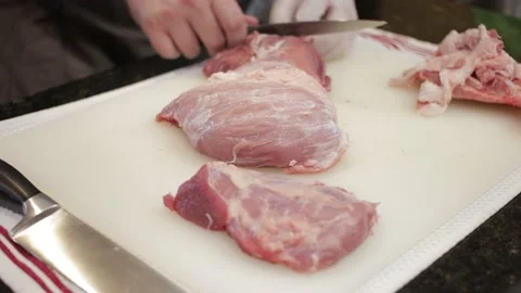 Man Cutting and trimming Large Pork Meat In A Kitchen With Two Knives Stock Footage 140615134
