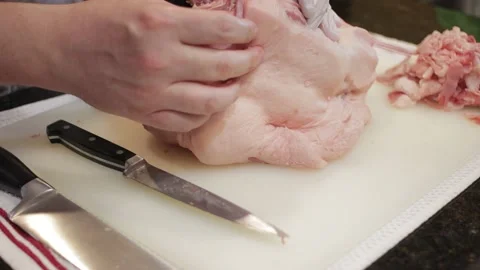 Man Cutting and trimming Large Pork Meat In A Kitchen With Two Knives Stock Footage 140615679