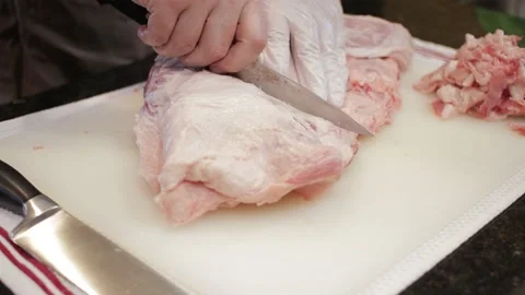 Man Cutting and trimming Large Pork Meat In A Kitchen With Two Knives Stock Footage 140616046