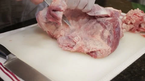 Man Cutting and trimming Large Pork Meat In A Kitchen With Two Knives Video stock 140616047