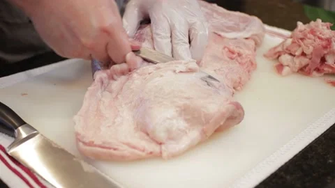 Man Cutting and trimming Large Pork Meat In A Kitchen With Two Knives Video stock 140616063