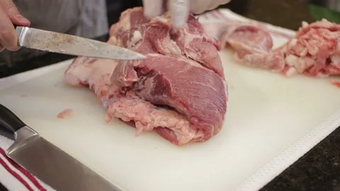Man Cutting and trimming Large Pork Meat In A Kitchen With Two Knives Stock Footage 140616295