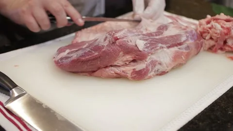 Man Cutting and trimming Large Pork Meat In A Kitchen With Two Knives Stock Footage 140616552