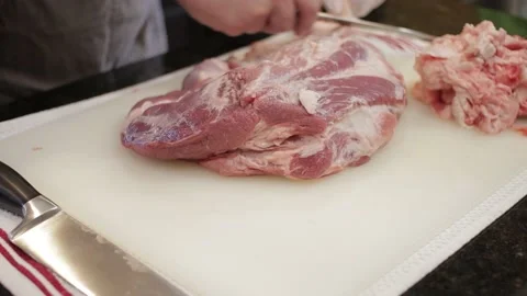Man Cutting and trimming Large Pork Meat In A Kitchen With Two Knives Video stock 140616611