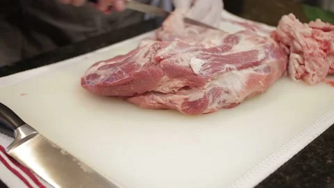 Man Cutting and trimming Large Pork Meat In A Kitchen With Two Knives Stock Footage 140616627