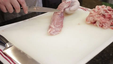 Man Cutting and trimming Large Pork Meat In A Kitchen With Two Knives Stock Footage 140616849