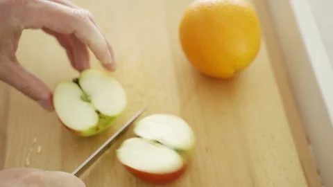 Man cutting an apple on a cutting board Видео 261079296