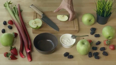 Man is cutting the apple for the fruit salad with yogurt in the spring time. Stock Footage 75623900
