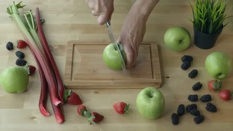 Man is cutting the apple into pieces  on the kitchen table view from above. Stock Footage 75621865