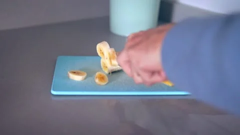 Man cutting banana on plastic cutting board Stock Footage