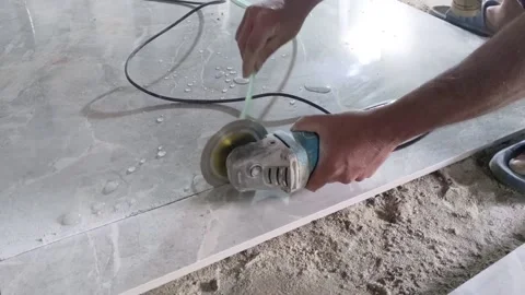 Man cutting a big floor tile with an angle grinder tool. A wet tile saw grinder Video stock 231763338