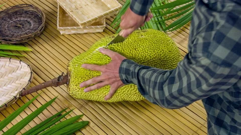 Man cutting big jackfruit on bamboo table. Top view on male hands and knife Vidéo 90781265