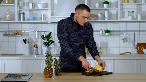 Man on a cutting board slices pineapple into circles 库存影片 127290117